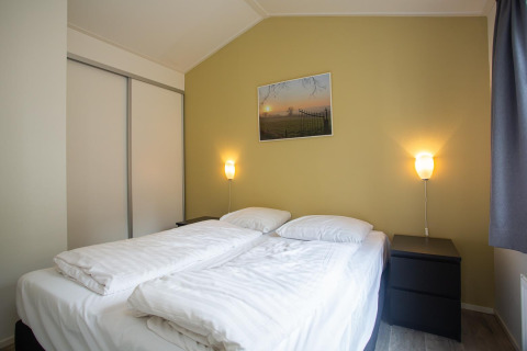Dormitorio en Heuvelrug Cottage Comfort en De Thijmse Berg, Países Bajos, con cama doble y luz cálida acogedora.