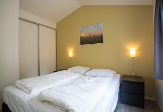 Dormitorio en Heuvelrug Cottage Comfort en De Thijmse Berg, Países Bajos, con cama doble y luz cálida acogedora.