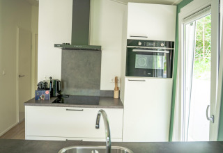 Cucina moderna nella Family Lodge con elettrodomestici, forno grande e vista patio a De Thijmse Berg, Paesi Bassi.