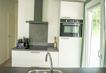 Moderne køkken i Family Lodge med apparater, stor ovn og udsigt til terrasse i De Thijmse Berg, Holland.