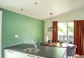 Cocina y comedor modernos en lodge familiar con pared verde en De Thijmse Berg, Países Bajos.