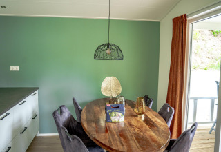 Comedor de Family Lodge en De Thijmse Berg con mesa ovalada, pared verde y vista a la terraza en Países Bajos.