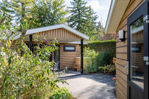 Außenbereich der Family Lodge + Hot Tub bei De Thijmse Berg in den Niederlanden mit viel Grün.