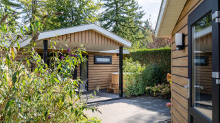 Außenbereich der Family Lodge + Hot Tub bei De Thijmse Berg in den Niederlanden mit viel Grün.
