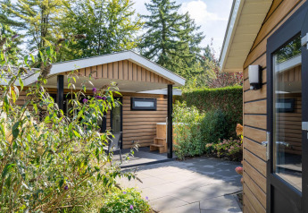 Außenbereich der Family Lodge + Hot Tub bei De Thijmse Berg in den Niederlanden mit viel Grün.