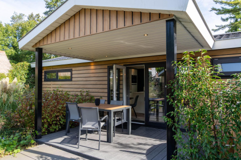 Buitenveranda van Family Lodge met tafel en stoelen, omgeven door groen op De Thijmse Berg, Nederland.