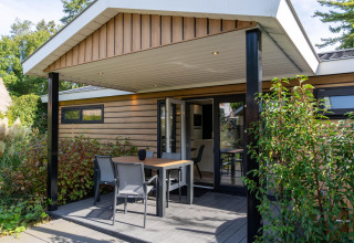 Udendørs terrasse ved Family Lodge med bord og stole, omgivet af grønt på De Thijmse Berg, Holland.