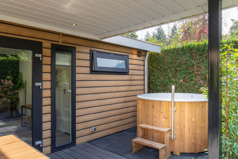 Buiten bubbelbad en eigentijdse houten lodge bij Family Lodge + hot tub, De Thijmse Berg, Nederland, groene omgeving.
