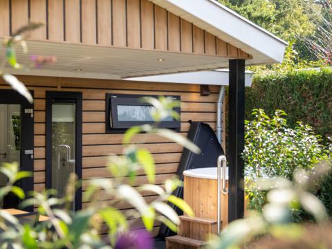 Buitenzicht op Family Lodge met houten bekleding en privé hottub op De Thijmse Berg in Nederland.