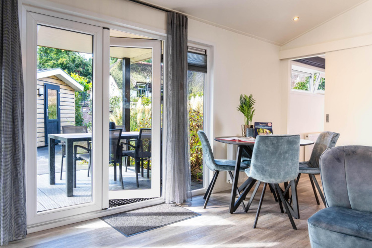 Interior view of Family Lodge at De Thijmse Berg, featuring dining space and terrace doors to outdoor seating.
