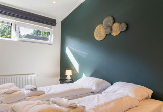 Dormitorio moderno en Family Lodge + jacuzzi en De Thijmse Berg, Países Bajos, con dos camas individuales y decoración.