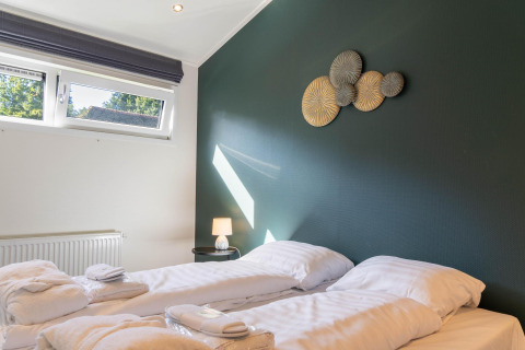 Modern slaapkamer in Family Lodge + hot tub op De Thijmse Berg, Nederland, met twee eenpersoonsbedden en decor.