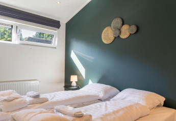 Chambre moderne à Family Lodge + jacuzzi à De Thijmse Berg, Pays-Bas, avec deux lits simples et décoration stylée.