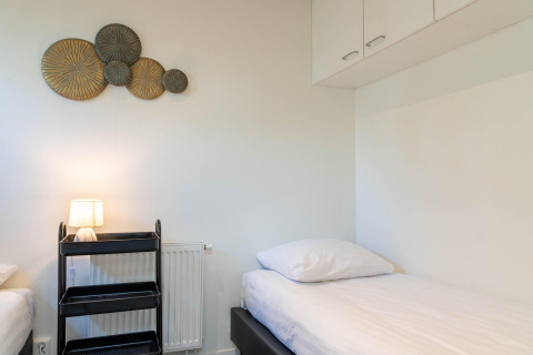 Kamer met twee eenpersoonsbedden, zwart rek, wanddecoratie en kasten in Family Lodge, De Thijmse Berg, Nederland.