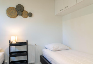 Kamer met twee eenpersoonsbedden, zwart rek, wanddecoratie en kasten in Family Lodge, De Thijmse Berg, Nederland.