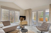 Lichte, moderne woonkamer in de Wellness Lodge op De Thijmse Berg, Nederland, met grote ramen en stijlvolle inrichting.