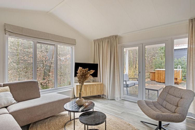 Salon lumineux et moderne à la Wellness Lodge de De Thijmse Berg, Pays-Bas, avec grandes fenêtres et déco élégante.