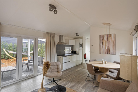 Moderne leefruimte van de Wellness Lodge bij De Thijmse Berg in Nederland met keuken en tuinzicht.