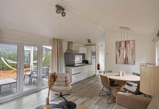 Moderne leefruimte van de Wellness Lodge bij De Thijmse Berg in Nederland met keuken en tuinzicht.