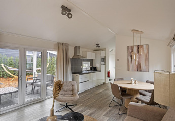 Moderne Wellness Lodge-stue på De Thijmse Berg i Holland med køkken, spisebord og udsigt til haven.