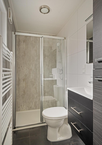 Baño moderno en Wellness Lodge de De Thijmse Berg, Países Bajos, con ducha y sanitario elegante.