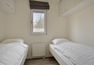 Camera con due letti singoli, finestra e mobili pensili presso Wellness Lodge a De Thijmse Berg, Paesi Bassi.