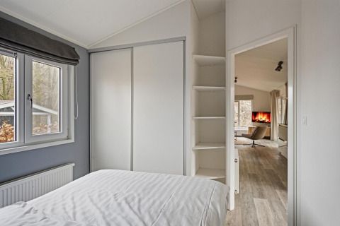 Dormitorio en Wellness Lodge en De Thijmse Berg, Países Bajos, con armario blanco y vista al salón.