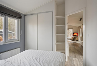 Chambre à la Wellness Lodge à De Thijmse Berg, Pays-Bas, avec armoire blanche et vue sur le salon.