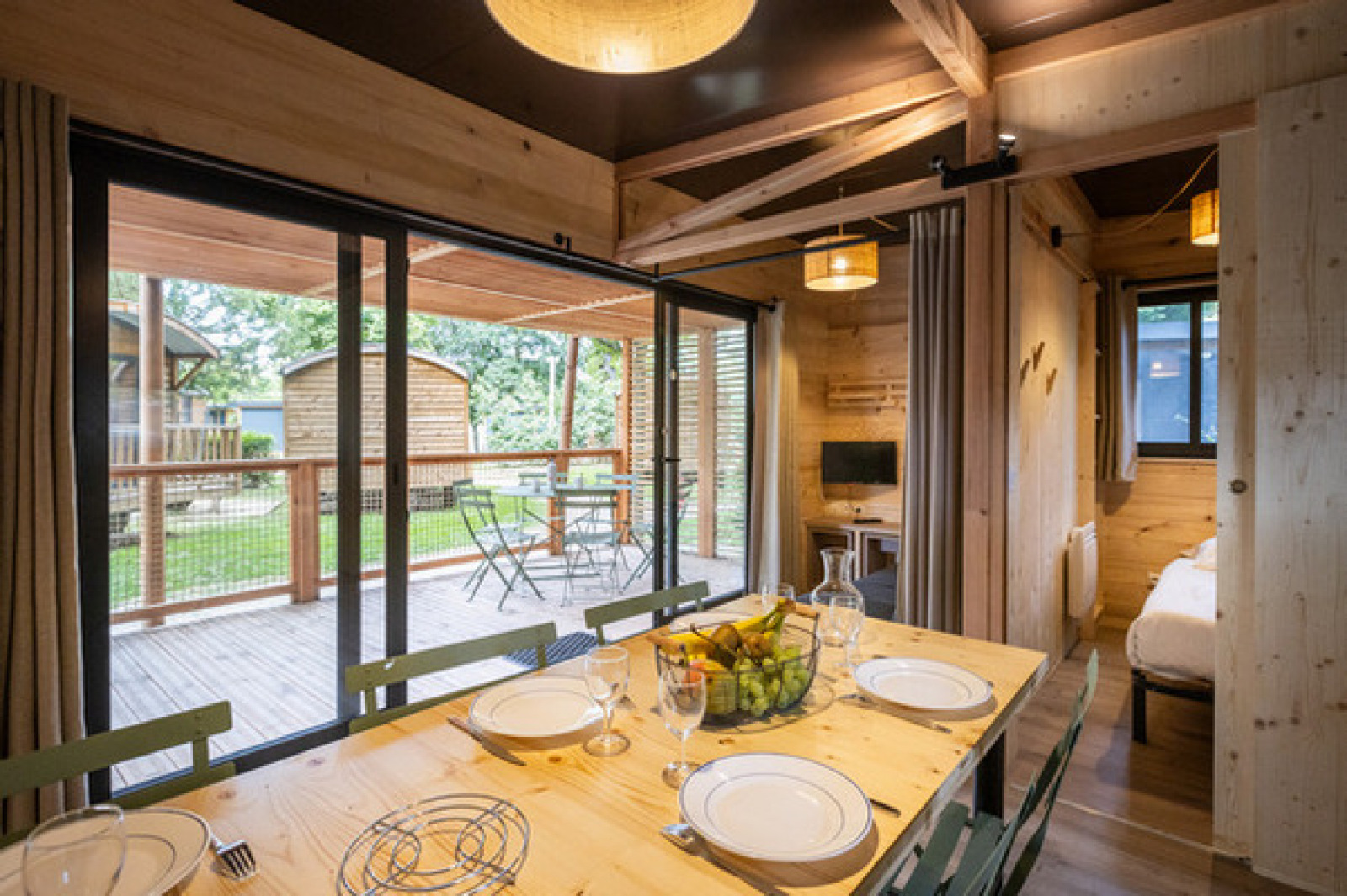 Mobile home Columbia bij Camping de Paris met eettafel, keuken en een terras uitkijkend op het groen