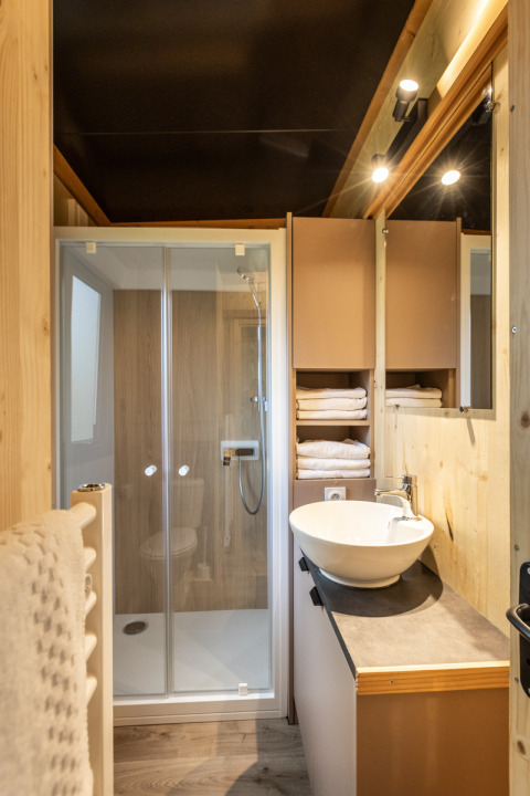 Baño moderno en Mobile home Columbia, Camping de Paris, con ducha, lavamanos y toallas blancas.