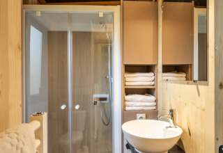 Baño moderno en Mobile home Columbia, Camping de Paris, con ducha, lavamanos y toallas blancas.