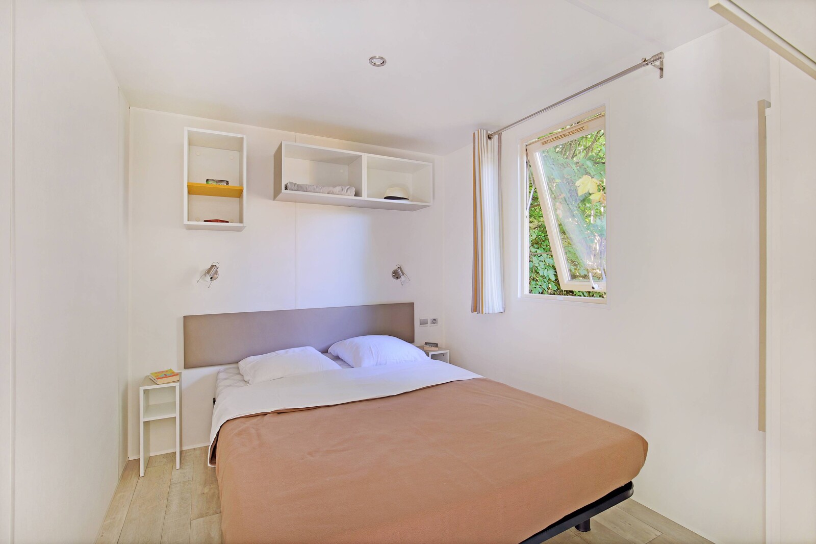 Moderne, minimalistische mobile home Cottage bij Camping de Strasbourg, met tweepersoonsbed en open raam.