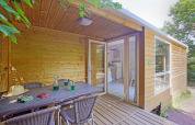 Hyggelig træhytte med overdækket terrasse og udendørs spisebord ved Camping de Strasbourg, Frankrig.