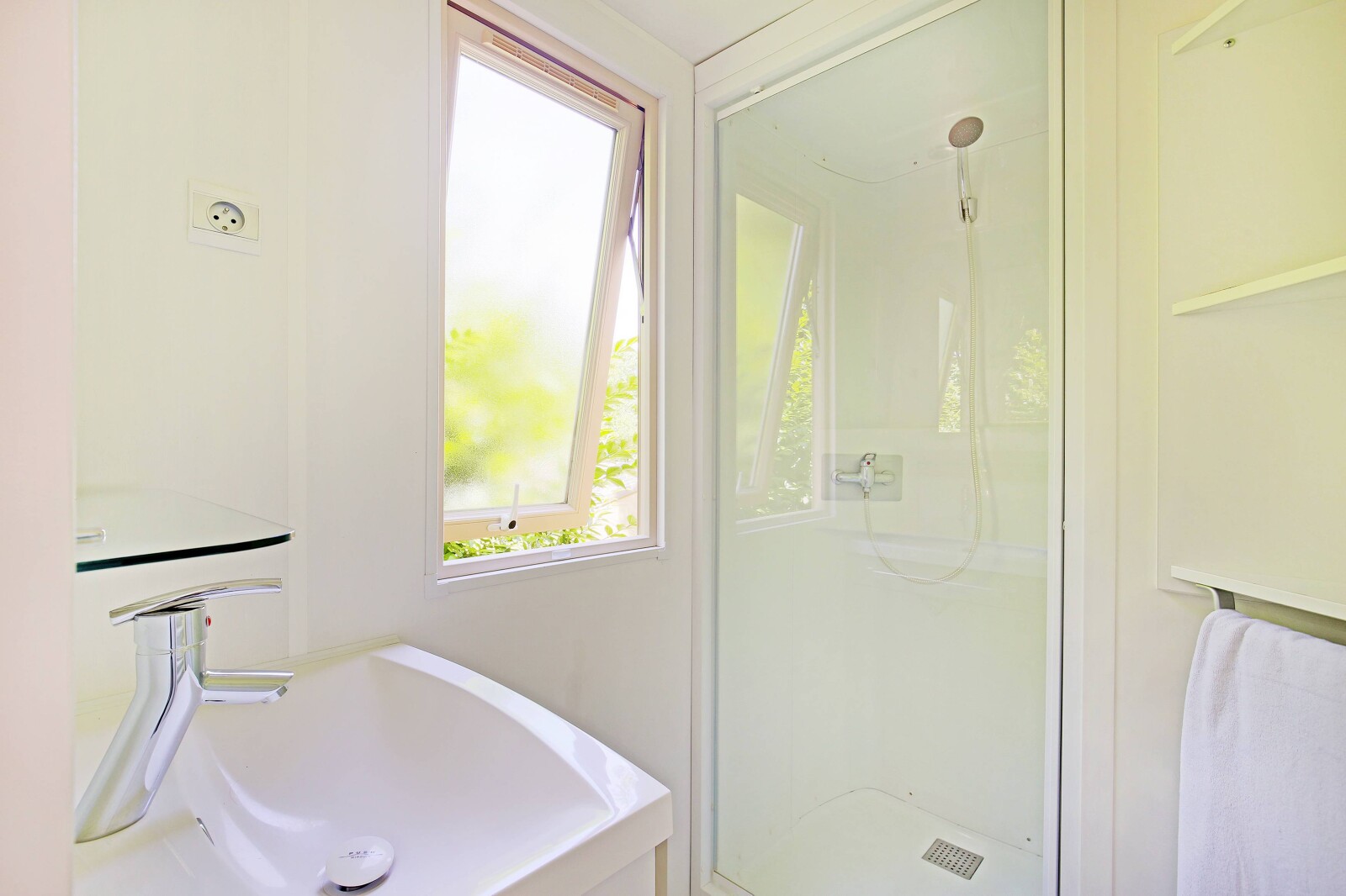 Lichte, moderne badkamer met douche, raam en wastafel in het Mobile home Cottage op Camping de Strasbourg.