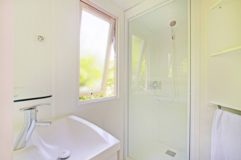 Lichte en moderne badkamer met douche, raam en lavabo in het Mobile home Cottage in Camping de Strasbourg.