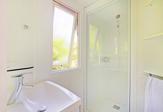 Helles, modernes Badezimmer mit Dusche, Fenster und Waschbecken im Mobile home Cottage auf Camping de Strasbourg.