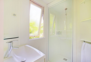 Lichte en moderne badkamer met douche, raam en lavabo in het Mobile home Cottage in Camping de Strasbourg.