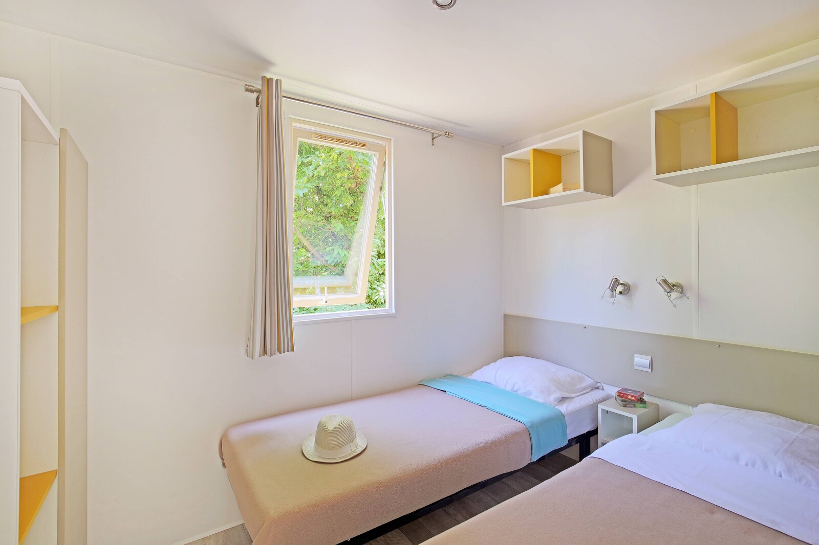 Lichte kamer met twee eenpersoonsbedden en open raam in Mobile home Cottage, Camping de Strasbourg.