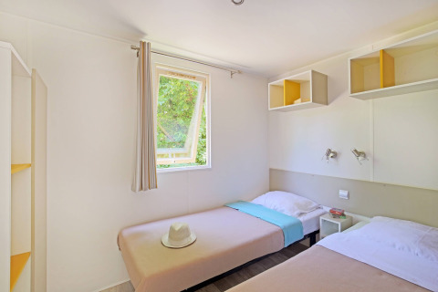 Lichte kamer met twee enkele bedden en open raam in Mobile home Cottage op Camping de Strasbourg.