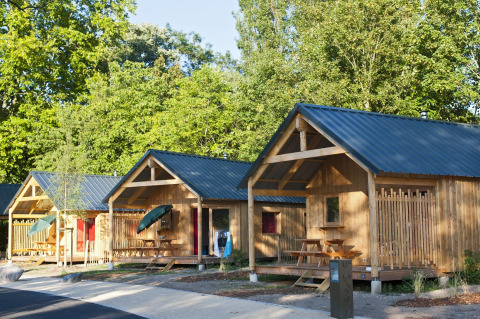 Photo of several cozy wooden cabins with porches and picnic tables at Chalet Montana, surrounded by trees.
