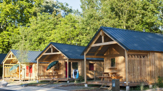 Foto de varias cabañas de madera con porches y mesas de picnic en Chalet Montana, rodeadas de árboles.