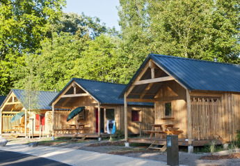 Foto di vari chalet in legno con verande e tavoli da picnic al Chalet Montana, circondati da alberi.