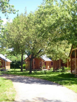 Zonnige houten chalets bij Chalet Montana, Camping de l'Ill - Colmar in Frankrijk, omgeven door bomen.