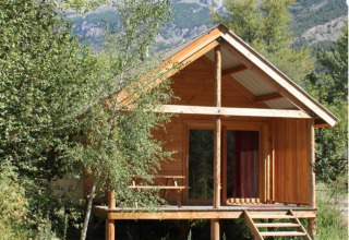 Cabaña de madera Chalet Montana en Camping de l'Ill - Colmar, Francia, rodeada de árboles y montañas.