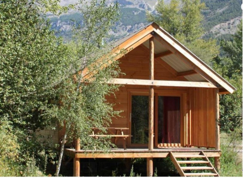 Wooden cabin named Chalet Montana at Camping de l'Ill - Colmar in France, surrounded by nature and trees.