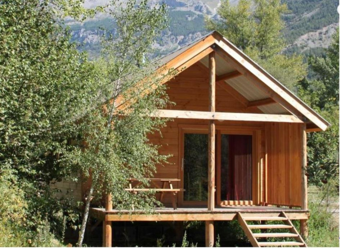 Wooden cabin named Chalet Montana at Camping de l'Ill - Colmar in France, surrounded by nature and trees.