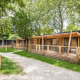 Træhytter ved Chalet Columbia omgivet af grønne træer og græs, med stier og en skyggefuld atmosfære.