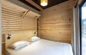 Dormitorio luminoso con paredes de madera y cama doble en Chalet Columbia, Camping de l'Ill - Colmar, Francia.