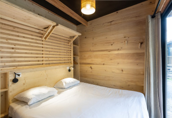 Camera luminosa con pareti in legno e letto matrimoniale allo Chalet Columbia, Camping de l'Ill - Colmar, Francia.