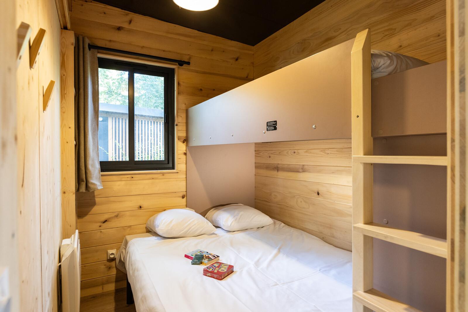 Knusse houten slaapkamer met tweepersoonsbed en stapelbed in Chalet Columbia op Camping de l'Ill - Colmar, Frankrijk.